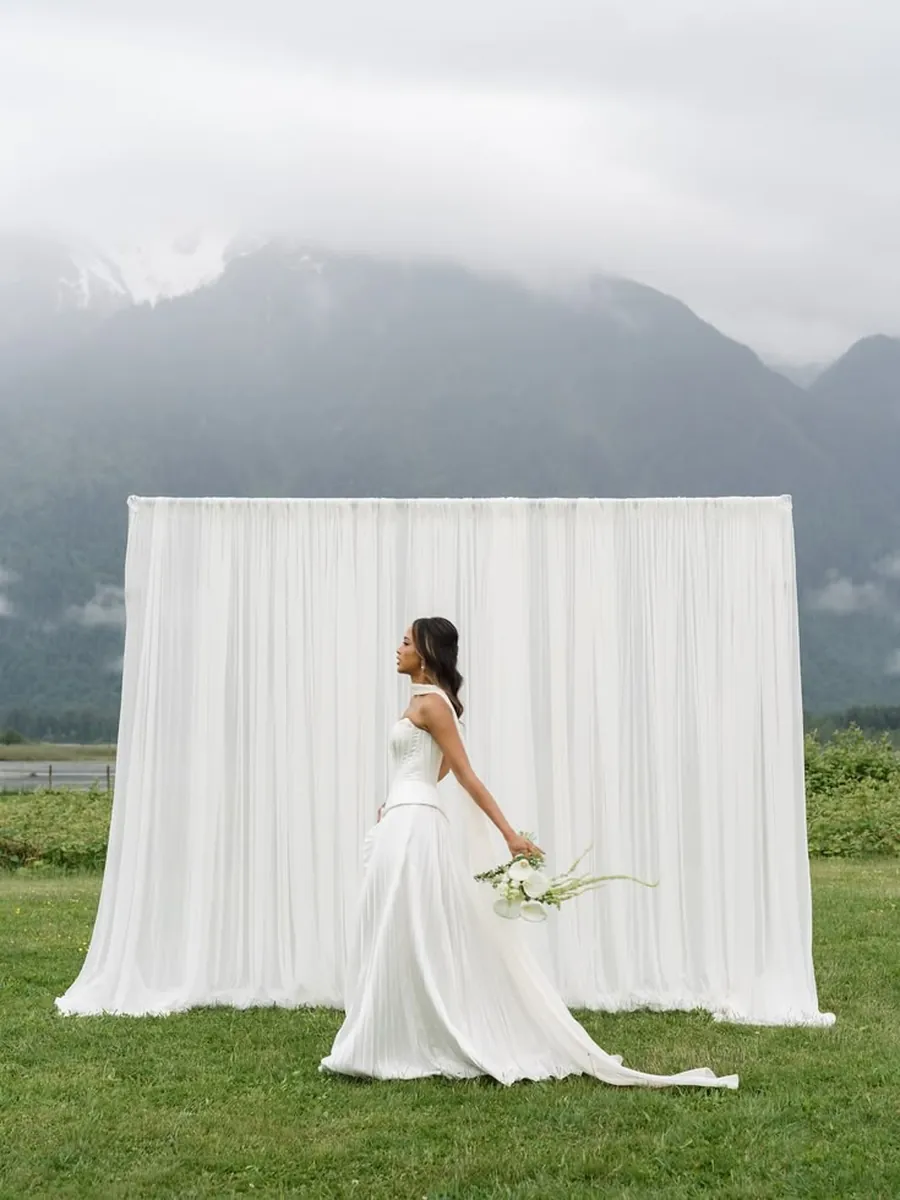 Novia de perfil delante del fondo del estudio, con la montaña al fondo